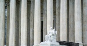 Supreme Court columns and seated justice statue at the building entrance