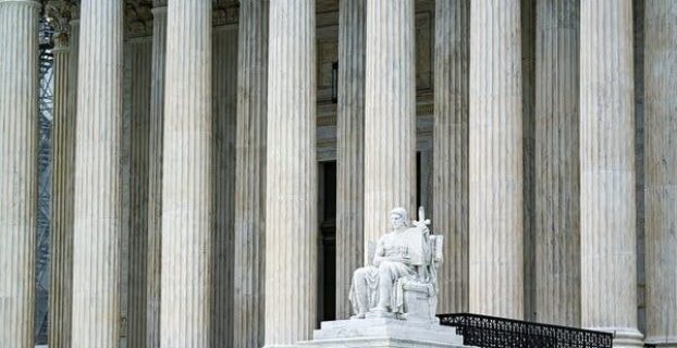 Supreme Court columns and seated justice statue at the building entrance