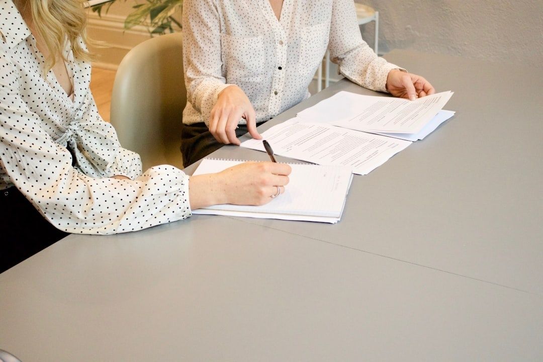 Two people review and sign legal documents at a desk