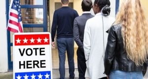 Voters enter a polling place beside a sign reading “VOTE HERE”
